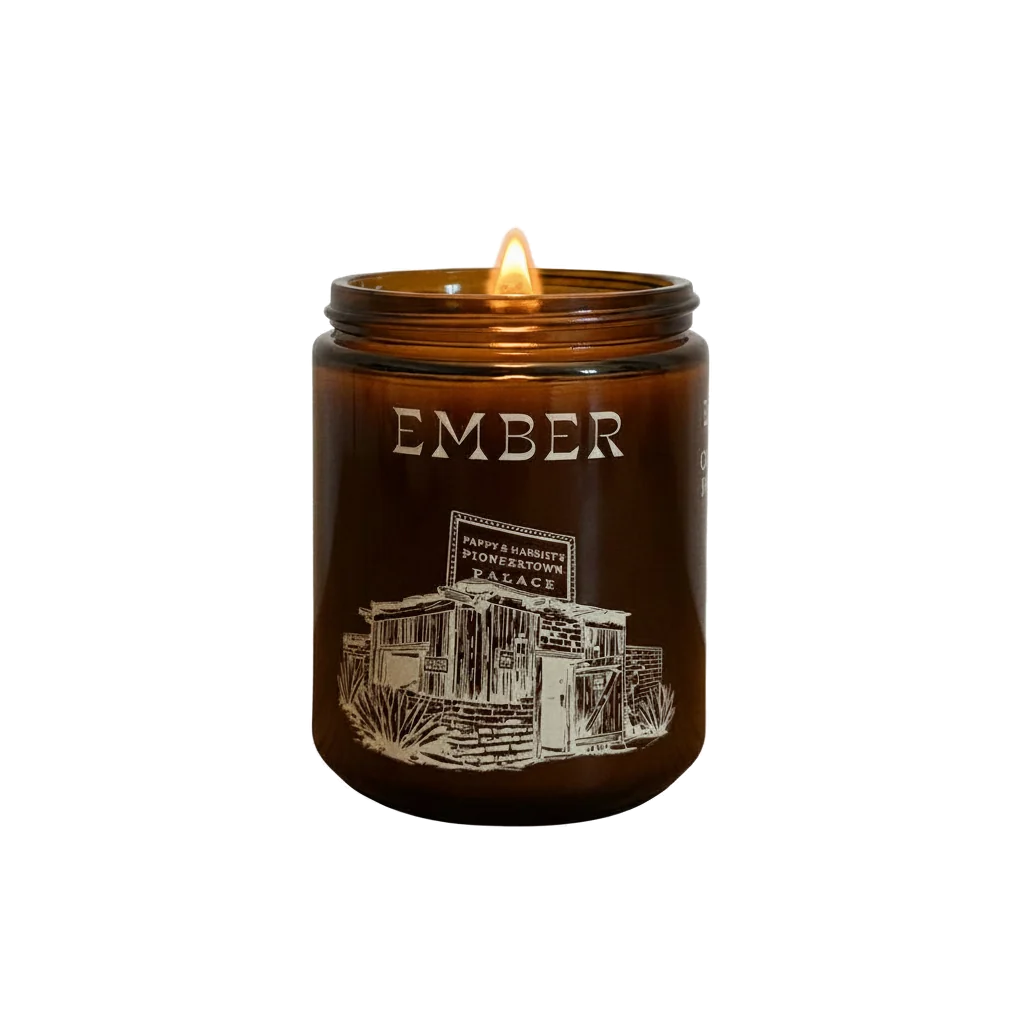 Ember candle in an amber glass jar, lit, with Pappy & Harriet's Pioneertown Palace illustration on the label