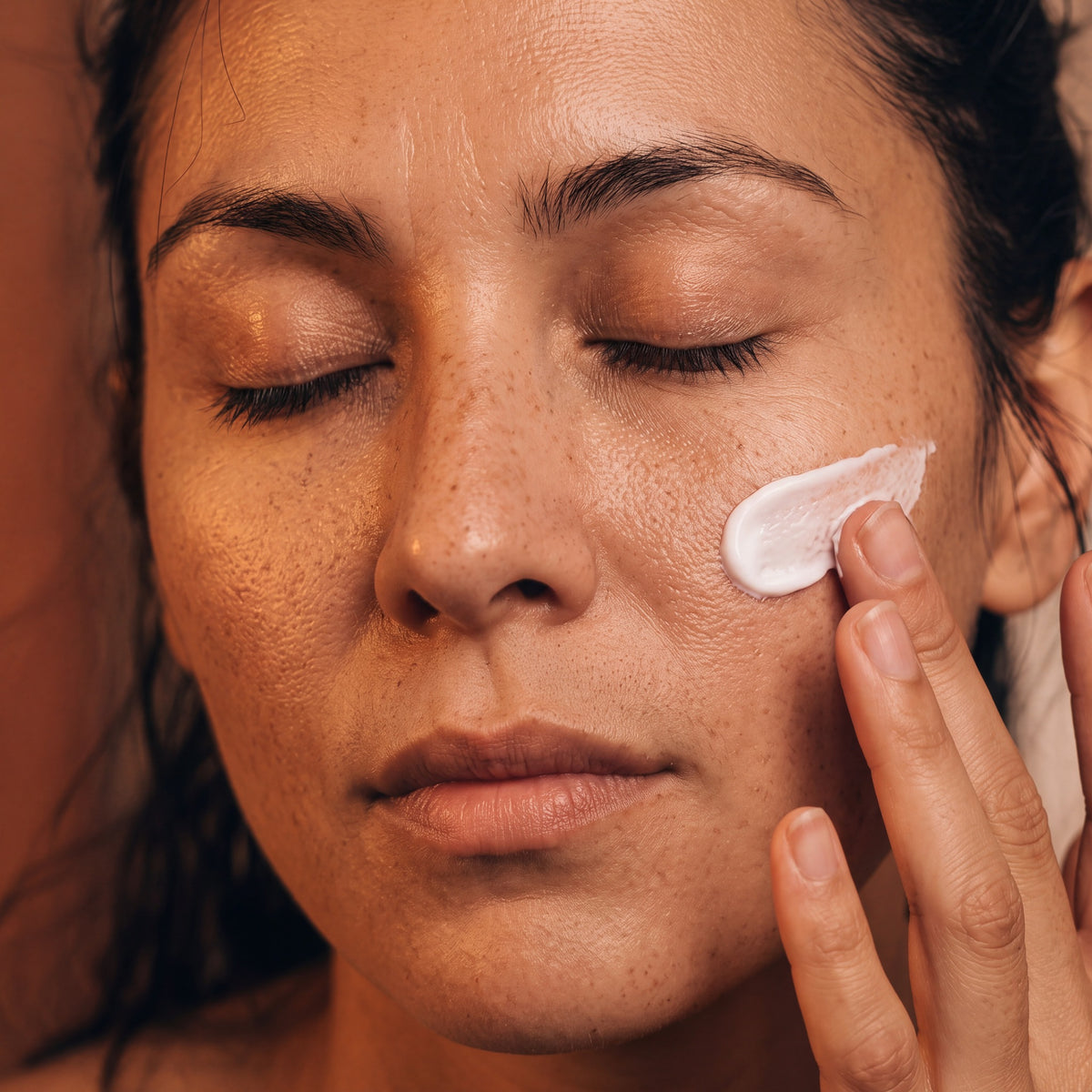 Model with eyes closed and a thin layer of Enzyme Cream Mask on her cheek