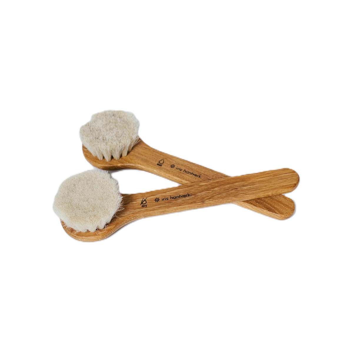 Two pale wooden brushes crossed on white