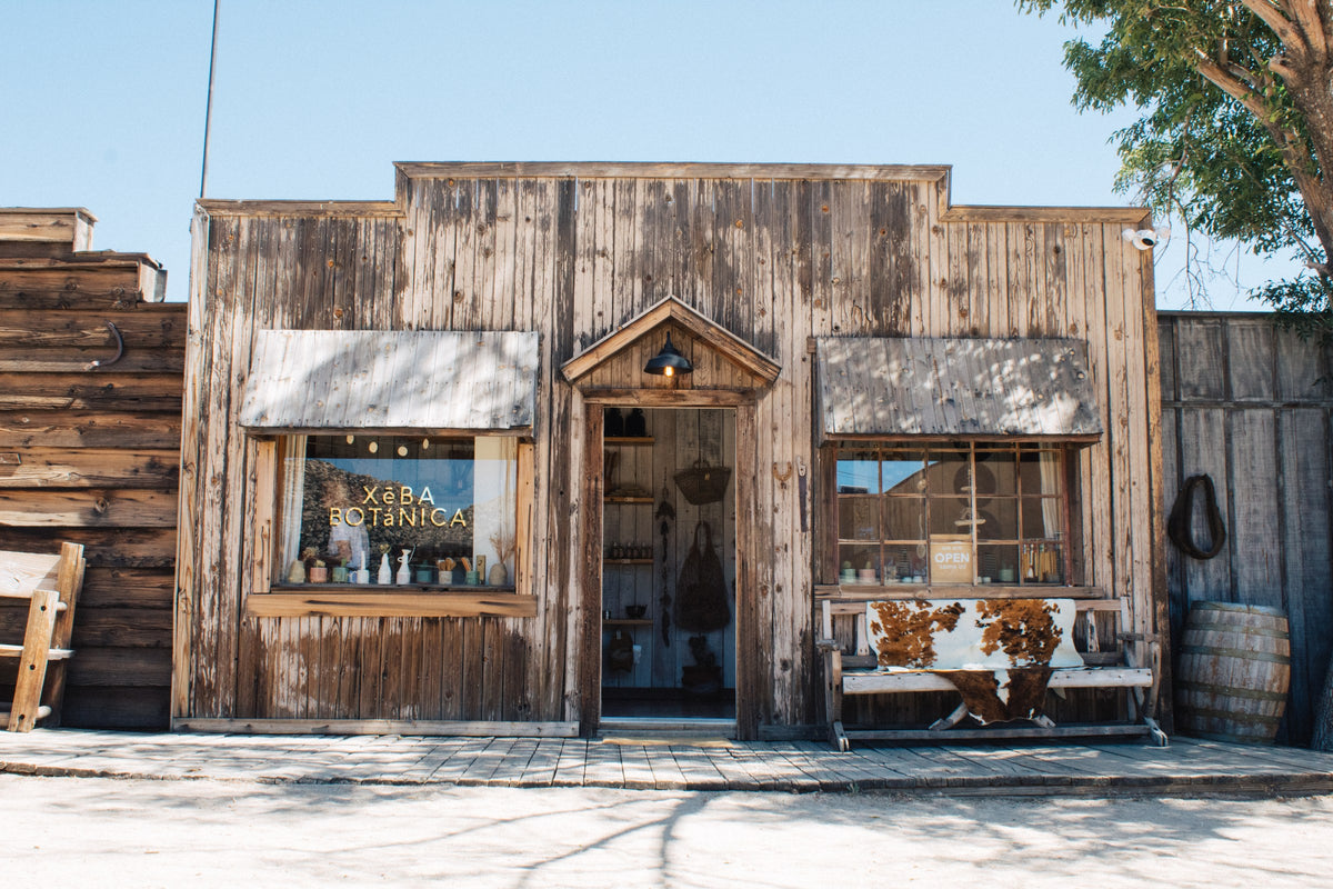The XēBA BOTáNICA storefront in Pioneertown, California: weathered wood facade, gold lettering in the window