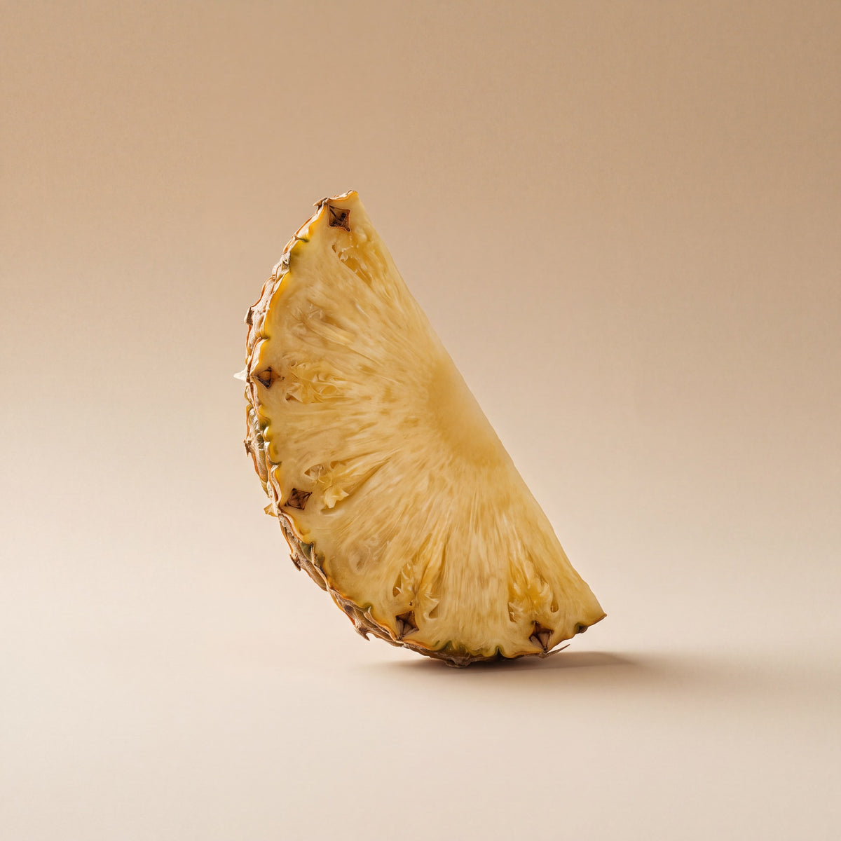 Fresh pineapple wedge, source of bromelain, on a warm sand backdrop