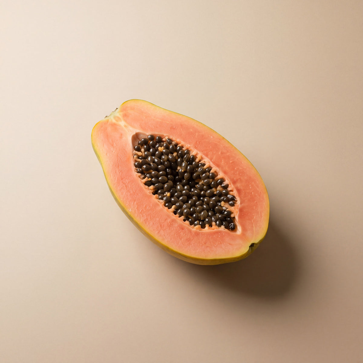 Halved papaya with black seeds, source of papain, on a warm sand backdrop