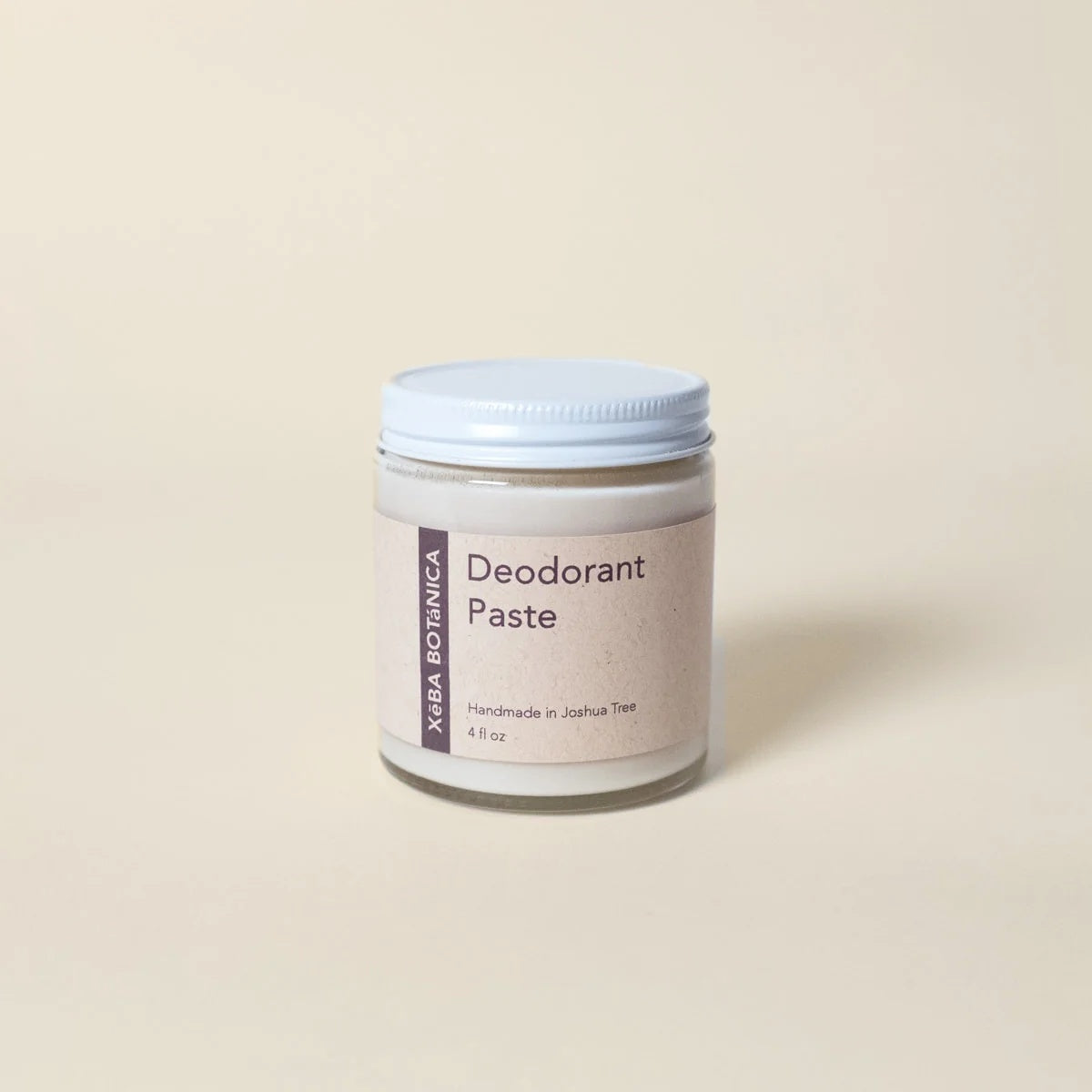 Xēba Botánica Deodorant Paste in a glass jar with a white lid, on a warm cream backdrop