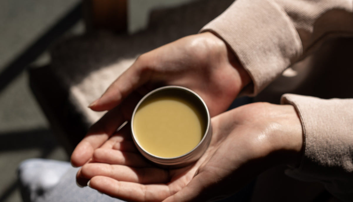 An open tin of Desert Balm cupped in two hands
