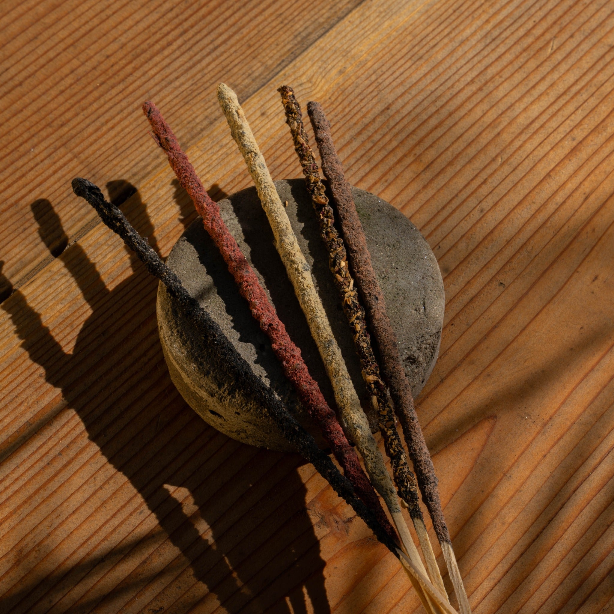 Bundle of hand-rolled incense sticks against a stone
